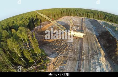 RUSSIA, VOSKRESENSK - JUL 1, 2014: Mestoli per escavatori e sabbia vicino alla foresta durante il tramonto. Vista aerea. Foto con rumore proveniente dalla Action camera. Foto Stock