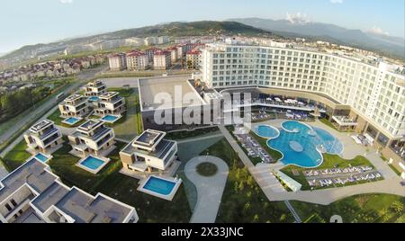 RUSSIA, SOCHI - 25 giugno 2014: Appartamenti privati vicino alla piscina comune con persone nell'hotel Radisson Blu nelle giornate di sole d'estate. Vista aerea. Foto con disturbo Foto Stock