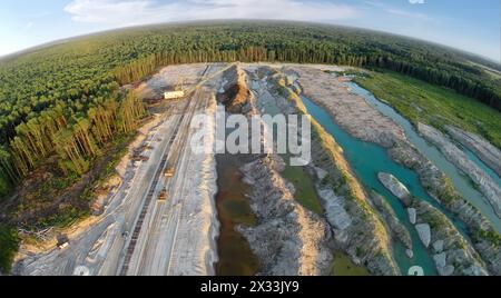 RUSSIA, VOSKRESENSK – JUL 1, 2014: L'escavatore sta lavorando vicino alla foresta e alla vecchia ferrovia. Vista aerea. (Foto con rumore proveniente dalla Action camera) Foto Stock