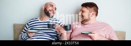 Due uomini siedono su un letto, riflettendo in compagnia degli altri, con un Bulldog francese nelle vicinanze. Foto Stock