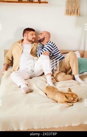 Due uomini stesi su un letto con il loro Bulldog francese accanto a loro. Foto Stock