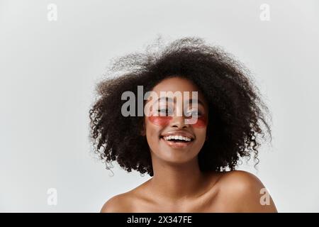 Una bella giovane donna afroamericana con capelli ricci che si esibiscono sotto le macchie per gli occhi Foto Stock