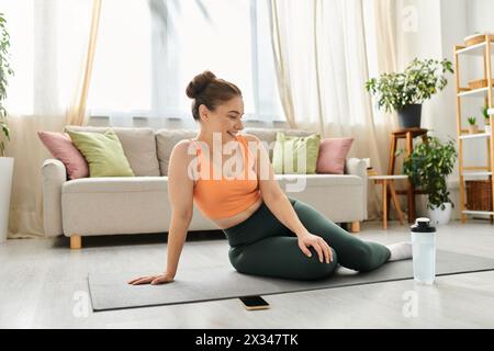 Una donna di mezza età si siede tranquillamente su un tappetino da yoga in un ambiente rilassato. Foto Stock