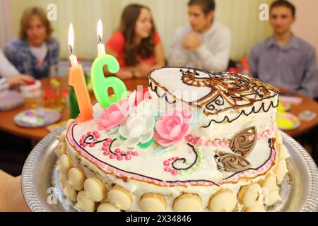 Bellissima torta di compleanno con sedici candele su un vassoio contro quattro adolescenti in classe Foto Stock