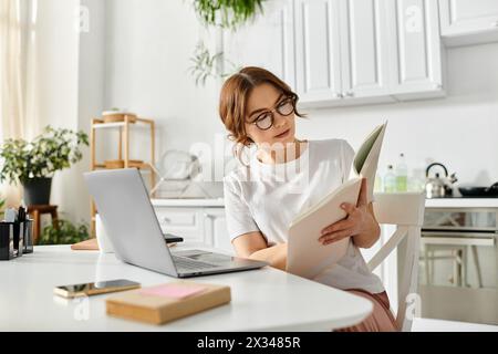 Donna di mezza età infilata in un libro a un accogliente tavolo da cucina. Foto Stock