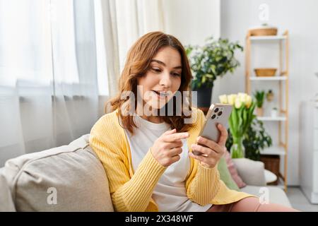 Donna di mezza età infilata nello smartphone sul divano. Foto Stock