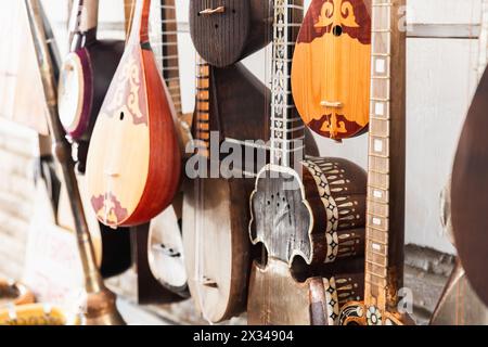 Una varietà di strumenti musicali a corde dell'Asia centrale sono messi in vendita in un bazar di Bukhara, foto ravvicinata con una messa a fuoco morbida e selettiva Foto Stock