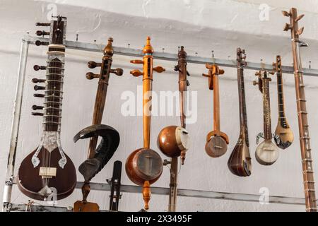 Una varietà di strumenti musicali a corde dell'Asia centrale sono messi in vendita in un bazar di Bukhara Foto Stock