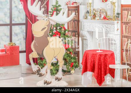 Interno natalizio con albero di Natale, caminetto, scatole regalo, candelabri, scaffali e alci di carta Foto Stock