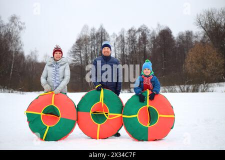 Mamma, padre e figlio felici posano con i tubi di neve in inverno Foto Stock