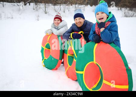 Madre, padre, figlio posano con i tubi di neve in inverno, concentratevi sul ragazzo Foto Stock