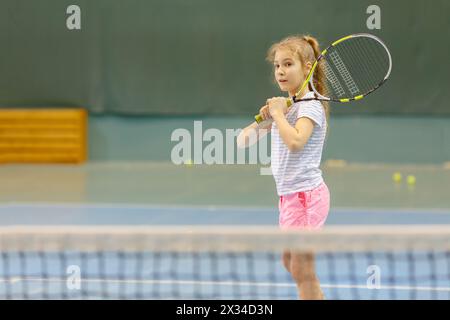 giovane ragazza sul campo da tennis in possesso di racchetta, in palestra, in attesa di servizio Foto Stock