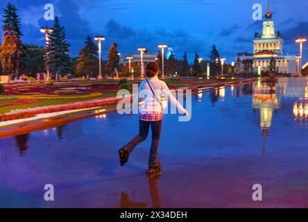 Giovane donna su pattini in una serata estiva nel parco Foto Stock