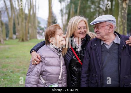 una famiglia si sta abbracciando in un parco. La famiglia è composta da una figlia e dai suoi genitori Foto Stock