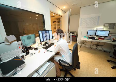 Medico esperto che esamina la scansione RM della regione lombare sul monitor nella sala di controllo Foto Stock