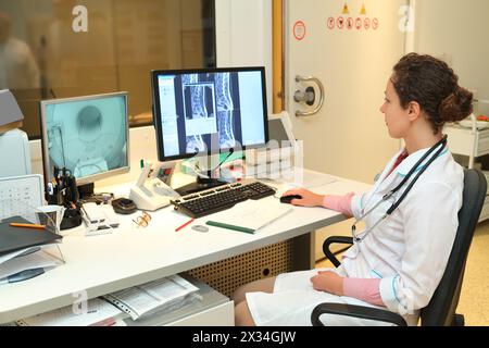 Medico esperto che esamina la scansione RM della regione lombare sul monitor Foto Stock