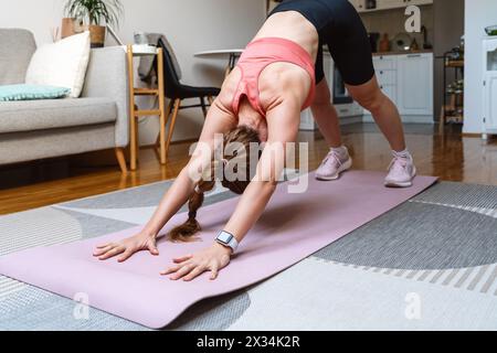 Una donna atletica si riscalda sul tappetino per esercizi a casa prima di allenarsi. Foto Stock