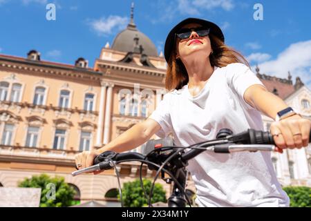 Una giovane donna urbana gira in bicicletta per la città. Foto ad angolo basso di una donna in bicicletta. Foto Stock