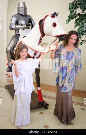 Donna e ragazza in costumi medievali parlano di cavaliere a cavallo Foto Stock