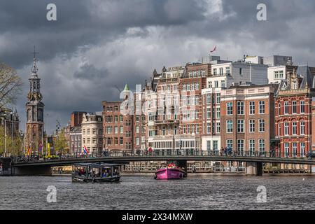 Il fiume Amstel e la torre storica Munt (Munttoren) a Muntplein ad Amsterdam, Paesi Bassi, con barche in primo piano. Foto Stock