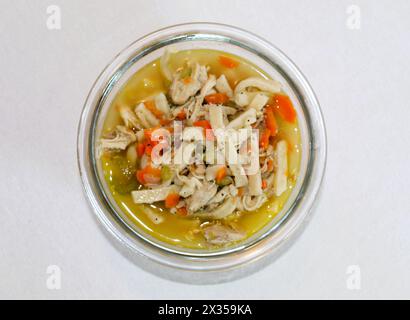 Zuppa di noodle di pollo fatta in casa in un recipiente di vetro con fondo semplice Foto Stock
