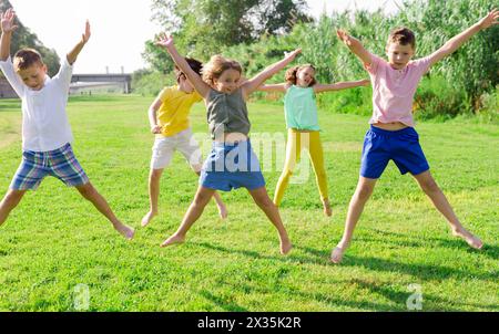 I bambini saltano e alzano le mani Foto Stock