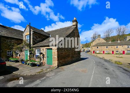 La strada principale che attraversa il villaggio Blanchland di Northumberland mostra lavori in pietra e spesse ardesia del tetto con cielo blu e nuvole bianche Foto Stock