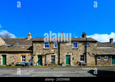 Una strada laterale attraverso il villaggio Blanchland di Northumberland che mostra lavori in pietra e spesse ardeie del tetto con cielo blu e nuvole bianche Foto Stock