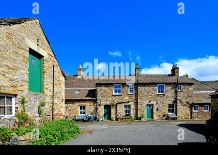 Una strada laterale attraverso il villaggio Blanchland di Northumberland che mostra lavori in pietra e spesse ardeie del tetto con cielo blu e nuvole bianche Foto Stock