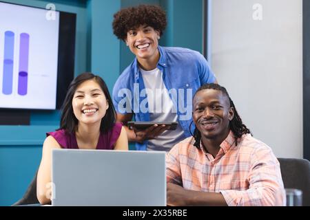 Gruppo eterogeneo di giovani colleghi che lavorano insieme in un moderno ufficio aziendale, sorridendo alla fotocamera Foto Stock