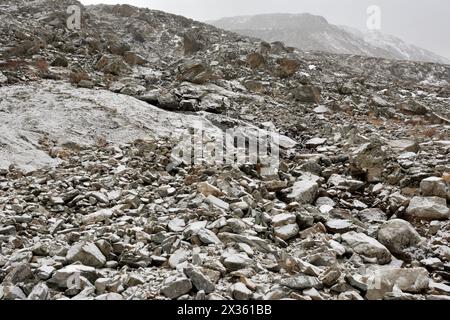 Vista dal basso sul ripido pendio della catena montuosa con una sparsa di grandi pietre polverate con la prima neve. Sailyugemsky Ridge, Altai, si Foto Stock