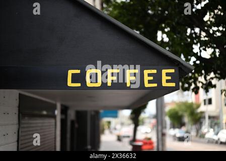 La parola caffè scritta in lettere gialle, o maiuscole, su una tenda nera sopra un negozio o un bar Foto Stock