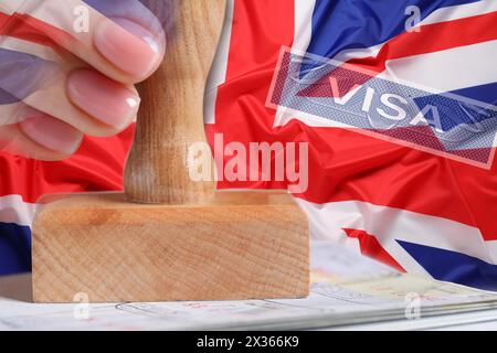 Esposizione multipla di donna che timbra la pagina del visto nel passaporto e bandiera della Gran Bretagna, primo piano Foto Stock