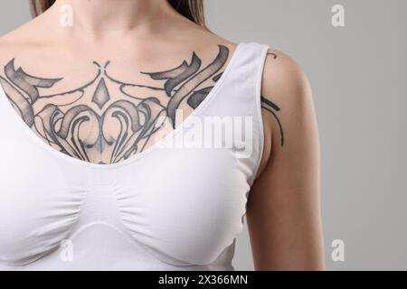 Donna con bellissimi tatuaggi su sfondo grigio, primo piano Foto Stock