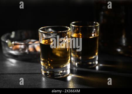 Dipendenza da alcol. Whisky in bicchieri su un tavolo di legno nero Foto Stock
