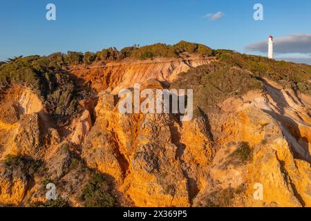 Vista distante di un faro bianco sulle scogliere erose sopra una costa frastagliata a Aireys Inlet sulla Great Ocean Road a Victoria, Australia Foto Stock