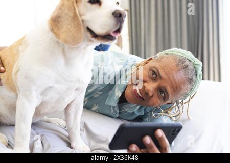 Una donna afroamericana anziana a letto si fa un selfie con il suo smartphone Foto Stock