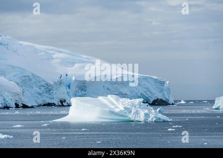 Un tranquillo paesaggio antartico, vicino al passaggio Graham lungo Charlotte Bay, che mette in evidenza forti riflessi, aspre montagne e suggestivi iceberg. Foto Stock