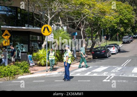 La poliziotta australiana dirige il traffico durante la sfilata ANZAC Day in Avalon Beach, Sydney, NSW, Australia, con il personale delle ambulanze St John di passaggio Foto Stock