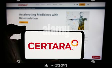 Persona che detiene un cellulare con il logo della società di biosimulazione statunitense Certara Inc. Di fronte alla pagina web aziendale. Mettere a fuoco il display del telefono. Foto Stock