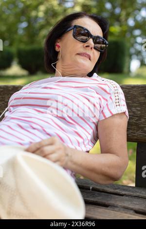 donna anziana che si rilassa su una panchina Foto Stock