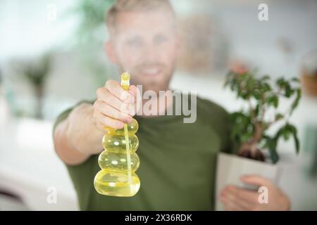 l'uomo che tiene in mano la pianta di casa spruzza la nebbia verso la telecamera Foto Stock