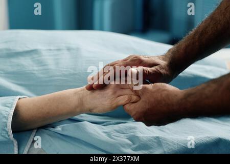 Medico maschile irriconoscibile che tiene per mano una donna caucasica matura prima della procedura di scansione TC in clinica moderna Foto Stock