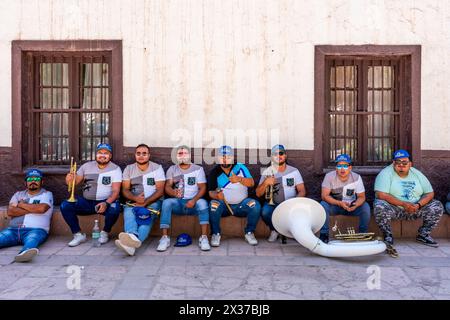 I musicisti riposano all'ombra prima di esibirsi a la Fiesta de la Virgen de la Candelaria, San Pedro de Atacama, regione di Antofagasta, Cile. Foto Stock