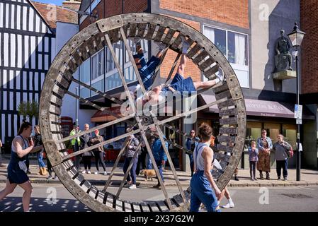 Sfilata celebrativa di Shakespeare con acrobati che rotolano una grande ruota di legno per le strade. 2024 Stratford Upon Avon, Inghilterra Regno Unito Foto Stock