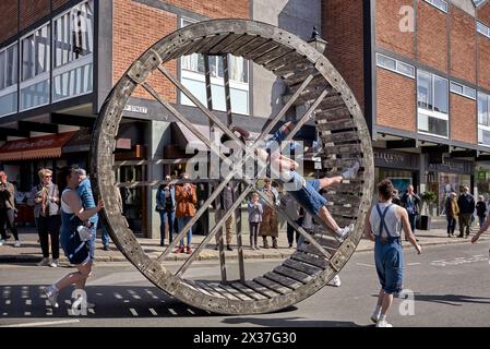 Sfilata celebrativa di Shakespeare con acrobati che rotolano una grande ruota di legno per le strade. 2024 Stratford Upon Avon, Inghilterra Regno Unito Foto Stock