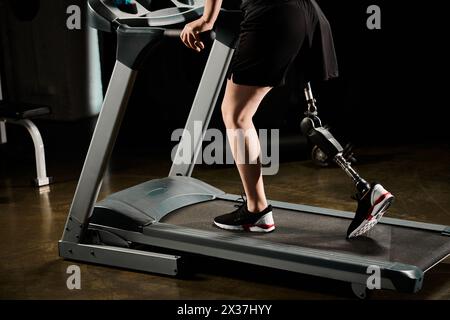 Un uomo determinato con una gamba protesica corre su un tapis roulant in palestra. Foto Stock