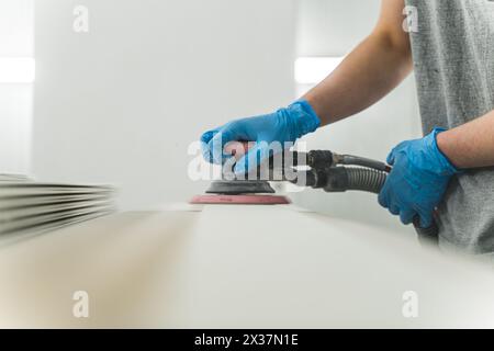 falegname che lavora nella sua officina. rifinisce la tavola di legno con carta vetrata. Foto di alta qualità Foto Stock