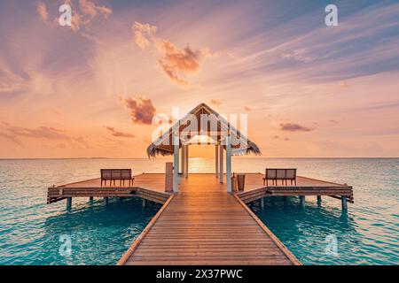 Incredibile alba, tramonto, vista sulla baia della spiaggia, colorate nuvole di cielo, molo di legno sopra il bungalow sull'acqua. Meditazione relax vista tropicale, mare oceano ispirare Foto Stock
