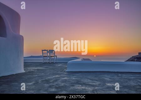 Terrazza con due sedie e vista sul mare al tramonto. Isola di Santorini, Grecia. Viaggi e vacanze. Il migliore paesaggio di viaggio per coppie romantiche Foto Stock